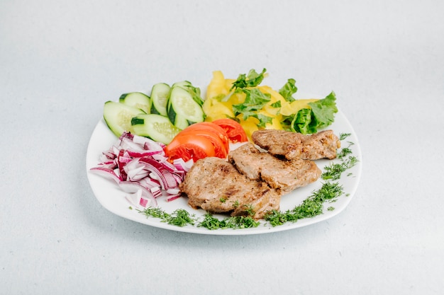 Barbacoa de carne con verduras y ensalada verde.