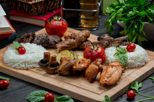 Barbacoa de cordero y pollo con guarnición de arroz en una tabla de bambú