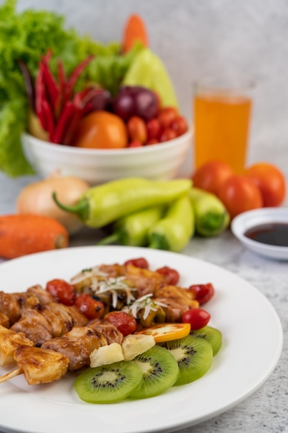 Barbacoa con una variedad de carnes, completa con tomates y pimientos en un plato blanco.