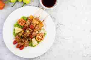 Foto gratuita barbacoa con una variedad de carnes, completa con tomates y pimientos en un plato blanco.