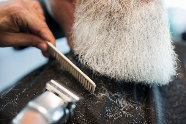 Barber corte barba al cliente en el salón