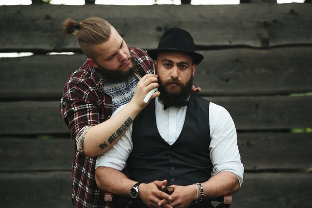 Foto gratuita barbero afeita a un hombre barbudo en ambiente vintage