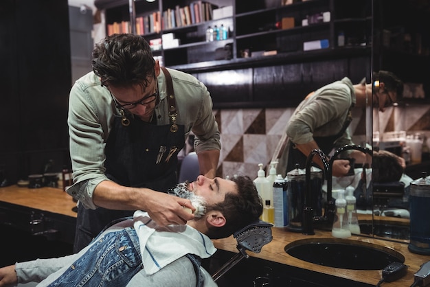 Barbero aplicando crema en la barba de los clientes