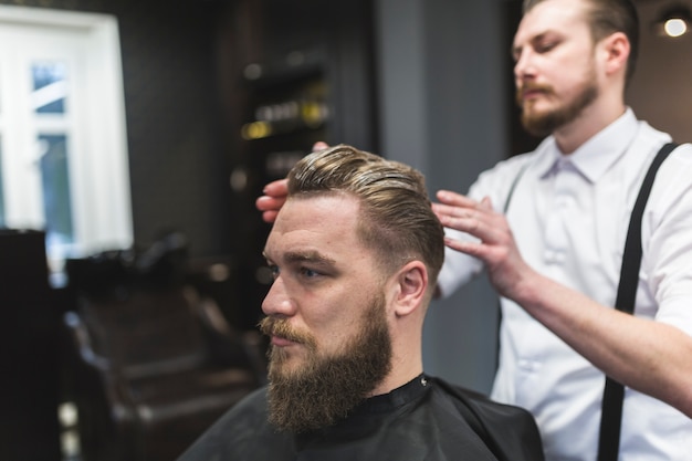 Barbero aplicando mousse en el cabello del cliente