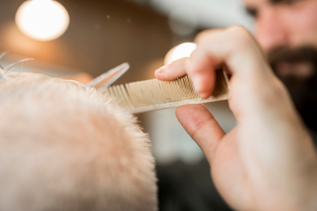 Foto gratuita barbero haciendo corte de pelo cliente