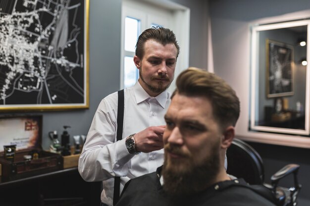 Barbero sirviendo al cliente barbudo