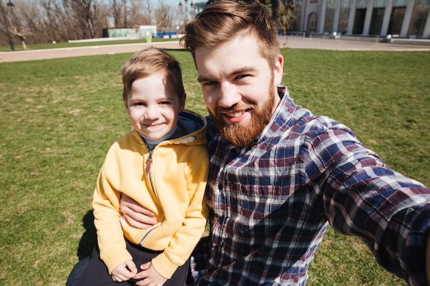 Barbudo padre sonriente al aire libre con su pequeño hijo