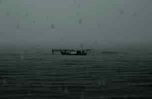 Foto gratuita barco abandonado lluvioso mar oscuro