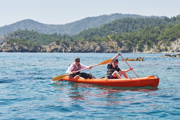 Barco en kayak cerca de los acantilados en un día soleado. Kayak en una bahía tranquila. Vistas increíbles. Viajes, concepto deportivo. Estilo de vida. Una familia feliz.