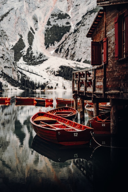 Foto gratuita barco de madera marrón sobre el agua cerca de la montaña cubierta de nieve durante el día