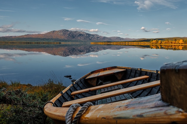 Barco de madera en la orilla de un gran lago hermoso y tranquilo