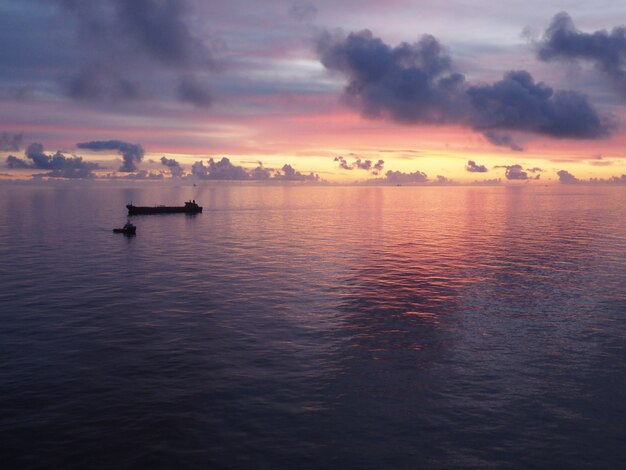 Barco en un mar bajo un cielo nublado durante una hermosa puesta de sol colorida en la noche