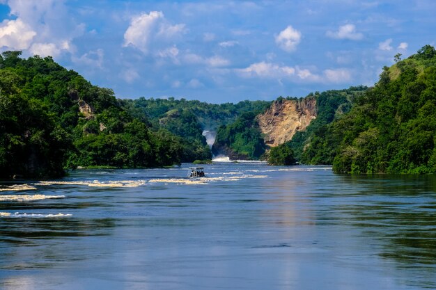 Barco navegando sobre el agua en medio de acantilados con árboles y plantas con cielo azul