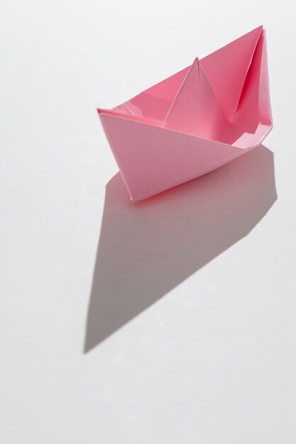 Barco de papel rosa sobre fondo blanco.