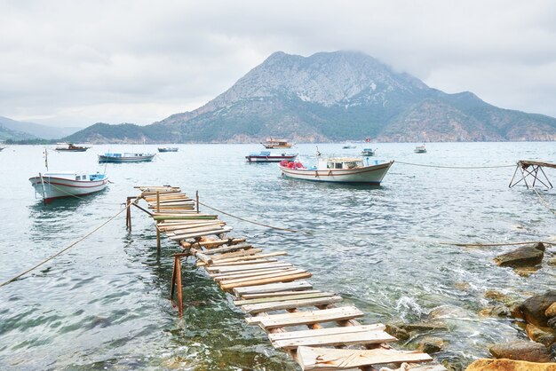 Barcos cerca del muelle roto, poniendo en un tranquilo mar azul tranquilo.