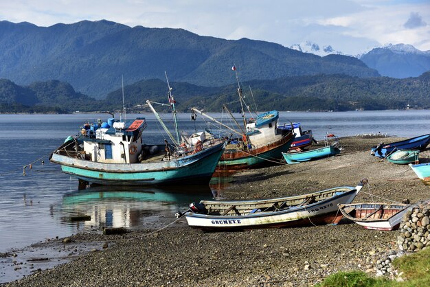 Barcos estacionados a orillas del lago con montañas