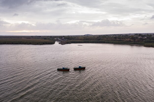 Barcos de pesca, flotando en las tranquilas aguas y yendo a pescar bajo un cielo con nubes