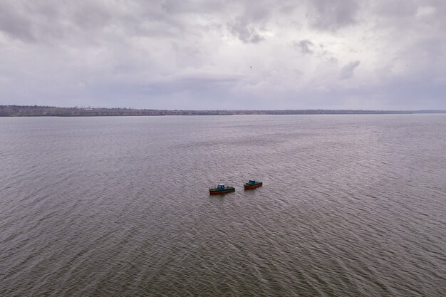 Barcos de pesca, flotando en las tranquilas aguas y yendo a pescar bajo un cielo con nubes