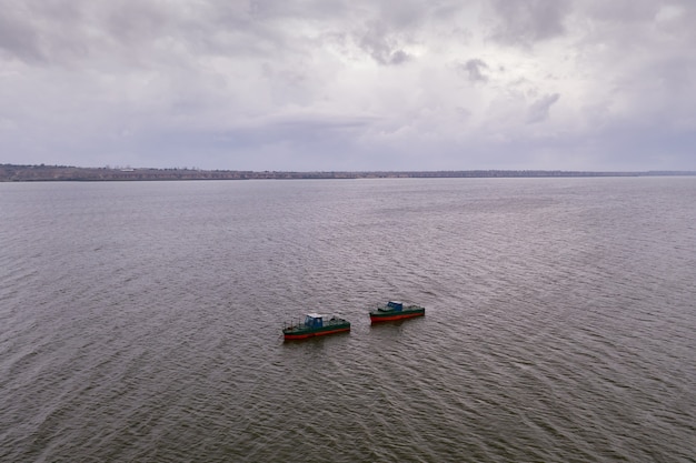 Barcos de pesca, flotando en las tranquilas aguas y yendo a pescar bajo un cielo con nubes