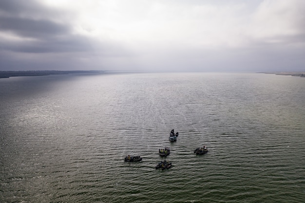 Barcos de pesca, flotando en las tranquilas aguas y yendo a pescar bajo un cielo con nubes