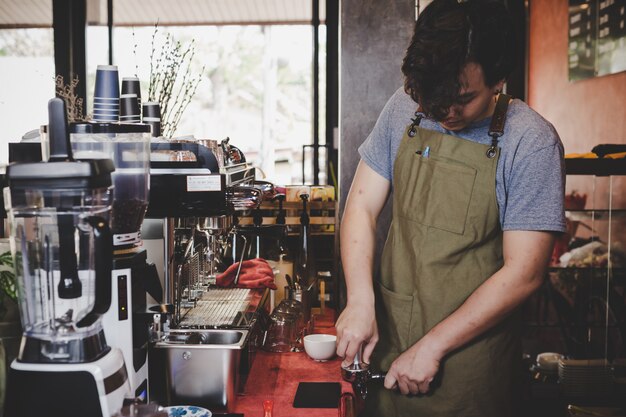 Barista Asia que prepara la taza de café para el cliente en cafetería.