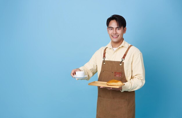 Un barista asiático feliz sirviendo a un cliente con una taza de café en una cafetería.