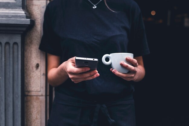 Barista de cultivo con bebida con teléfono inteligente