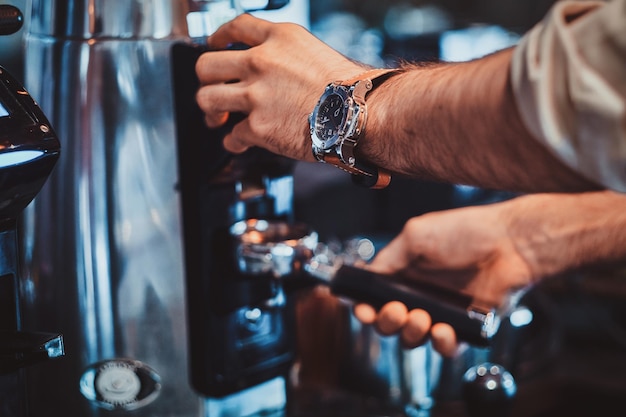 El barista diligente está preparando un café con leche fresco para los clientes para tomar un café en la cafetería.