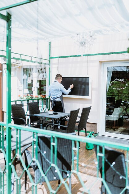 Barista escribiendo en pizarra en terraza