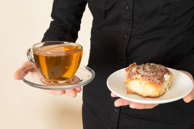 Barista femenina en pantalones de camisa negra con café café ingredientes de equipo de té seco en la pared blanca