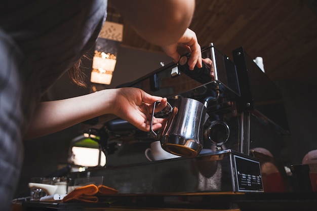 Barista femenina prepara café expreso de una máquina de café en la cafetería.