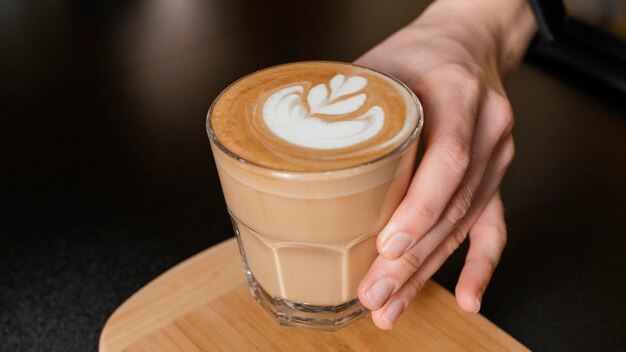 Barista femenina sosteniendo un vaso de café decorado