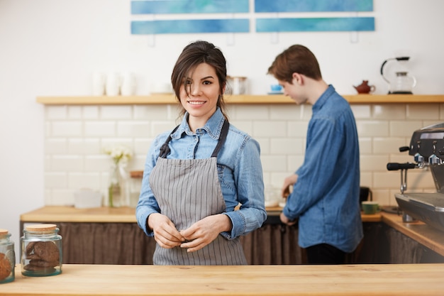 Foto gratuita barista femenina en uniforme sonriendo alegremente tomando órdenes.