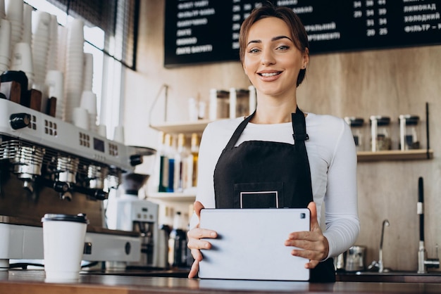 Barista femenino con orden de fabricación de tableta en una cafetería.