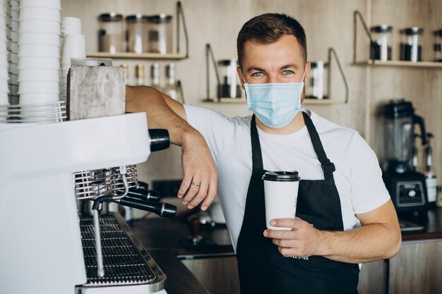 Barista macho sosteniendo café en taza de cartón