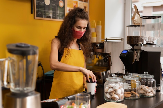 Barista con una máscara médica en el trabajo