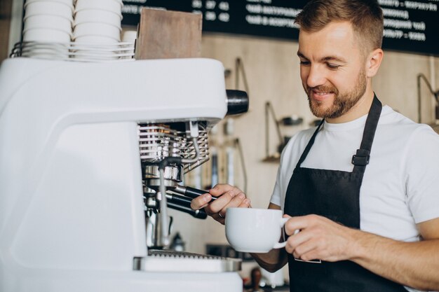 Barista masculino en la cafetería sosteniendo la taza por el mostrador