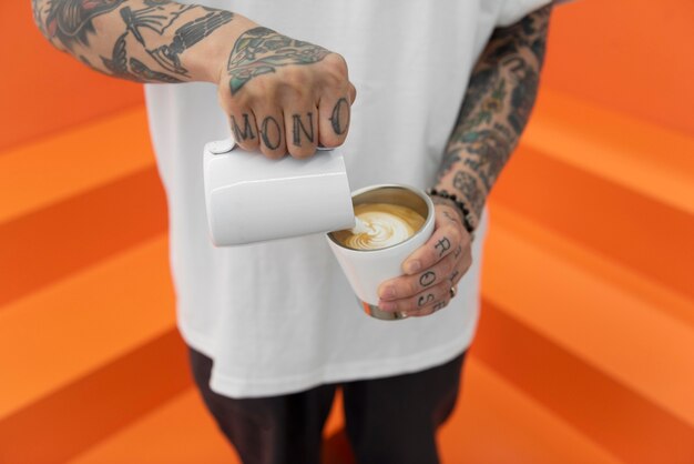 Barista masculino con tatuajes añadiendo leche al café