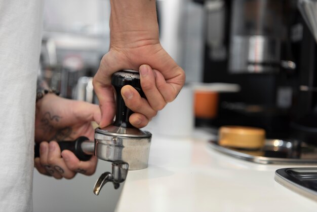 Barista masculino con tatuajes preparando café para la máquina de café