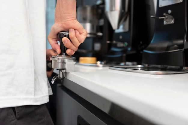 Barista masculino con tatuajes en el trabajo con la máquina de café