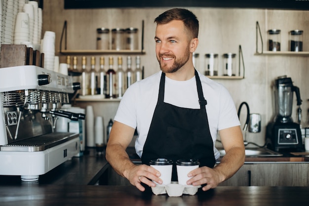 Barista de pie junto al mostrador en una cafetería.