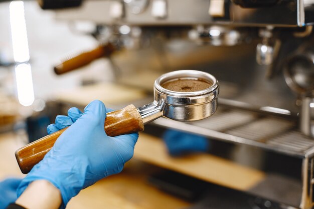 Barista prepara café. Café en soporte. Manos enguantadas.