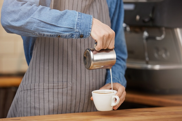 Barista prepara una taza de café con leche para el cliente en la cafetería.
