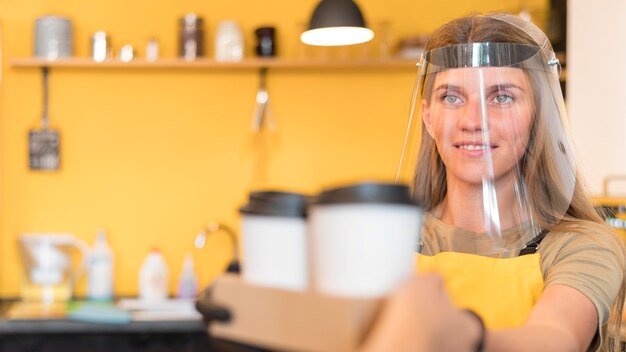 Barista con protección facial cuando sirve