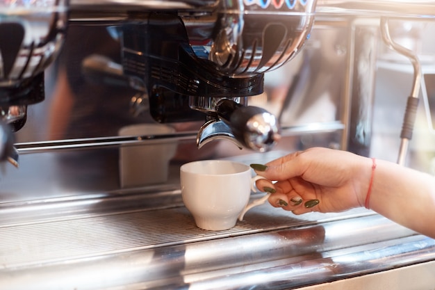 Barista sin rostro haciendo un sabroso café a través de una máquina de café