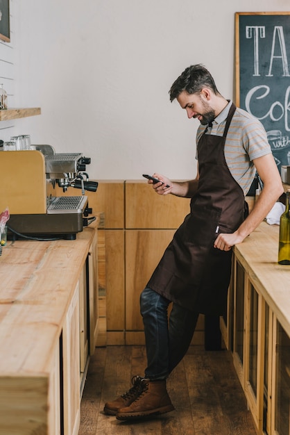 Barista sonriente que usa smartphone