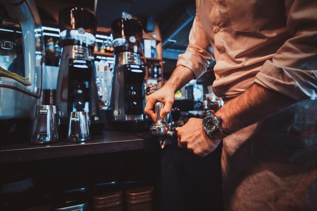 El barista talentoso está preparando café para los clientes en un restaurante elegante usando una máquina de café.