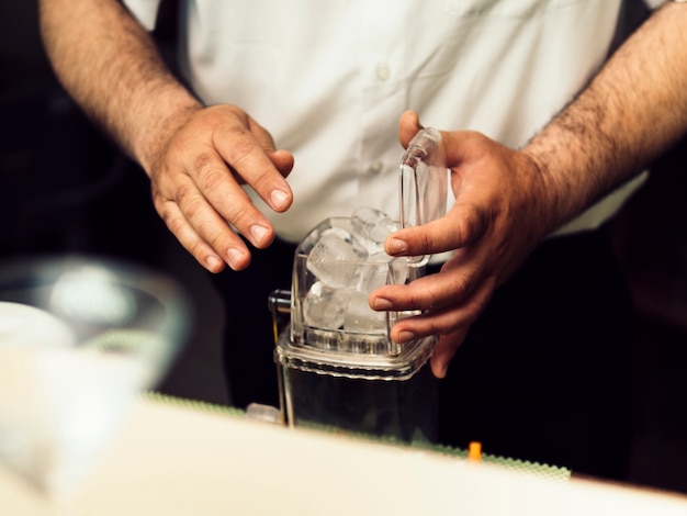 Barkeeper poniendo hielo en la caja para moler