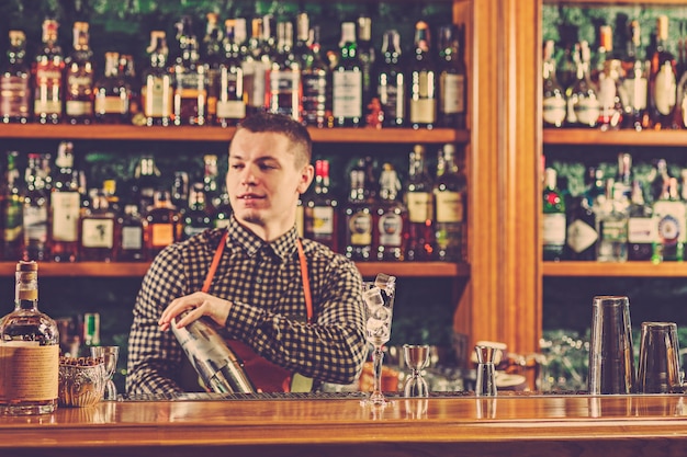 Foto gratuita el barman haciendo un cóctel alcohólico en el mostrador del bar en el espacio del bar.