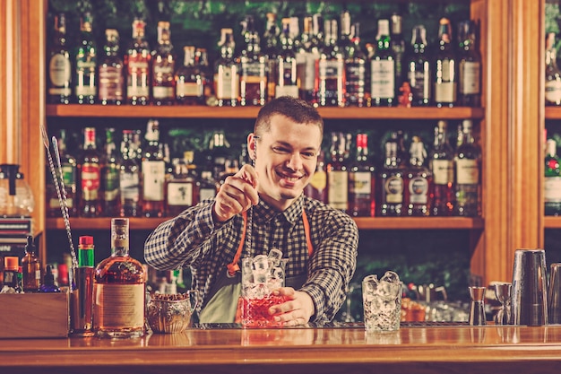 El barman haciendo un cóctel alcohólico en el mostrador del bar en el espacio del bar.